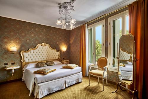 a bedroom with a bed and a chair and windows at Hotel Gardena in Venice