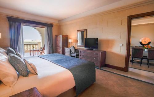 a hotel room with a bed and a television at Kempinski Hotel San Lawrenz in San Lawrenz