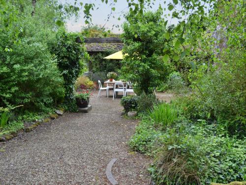 a patio with a table and umbrella in a garden at Arne Barn in Arne