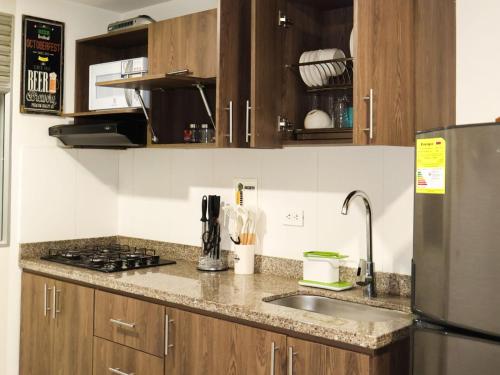 a kitchen with a sink and a stainless steel refrigerator at Loft Moderno en Sabaneta Estilo Confort y Conexión in Sabaneta