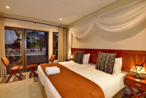 a bedroom with a large bed and a large window at Hwange Safari Lodge in Dete