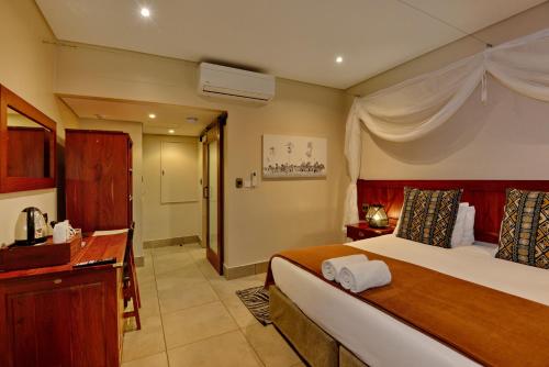 a hotel room with a bed and a bathroom at Hwange Safari Lodge in Dete