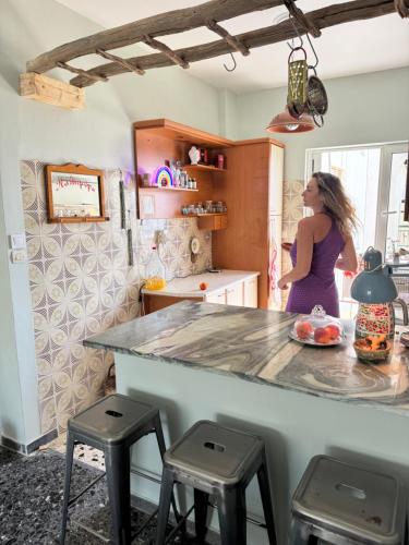 a woman standing at a counter in a kitchen at Seaside Retro Gem in the Heart of Karystos in Athens