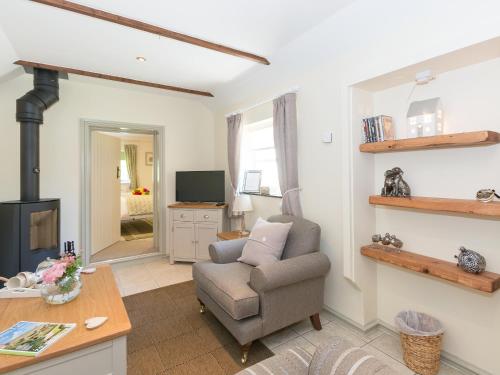 a living room with a chair and a television at Cherry Blossom in Thornton Dale