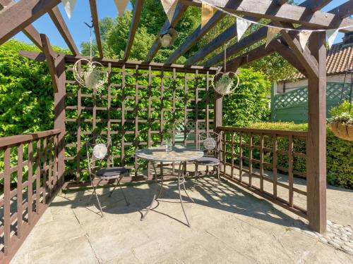a pergola with a table and chairs on a patio at Cherry Blossom in Thornton Dale