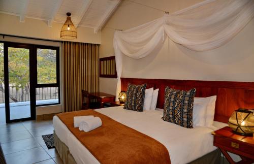 a bedroom with a large bed with white sheets and pillows at Hwange Safari Lodge in Dete