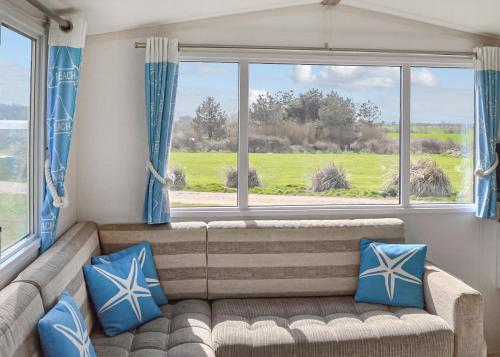 a living room with a couch and a large window at Anchor Park in Happisburgh