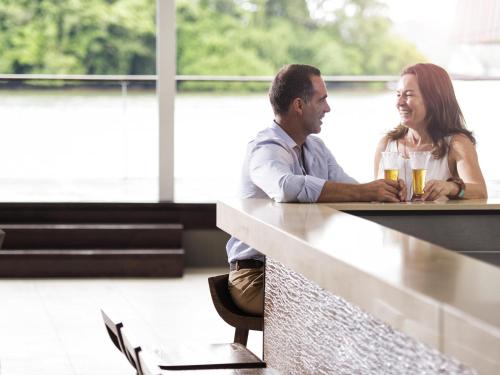a man and woman sitting at a bar with drinks at Novotel Suva Lami Bay in Suva
