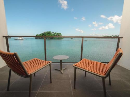 two chairs and a table on a balcony with a view of the water at Novotel Suva Lami Bay in Suva