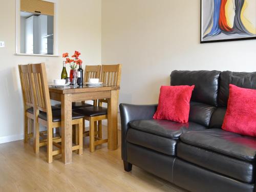 a living room with a black leather couch and a table at Riverside Mews in Bideford