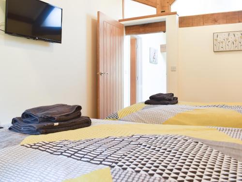 a bedroom with two beds and a flat screen tv at North Barn in Monk Okehampton