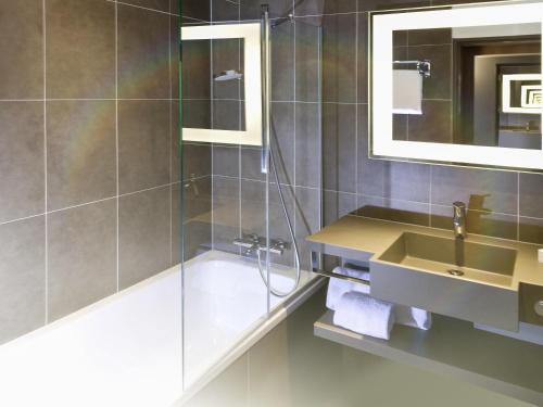 a bathroom with a shower and a sink and a mirror at Novotel London Brentford in Brentford
