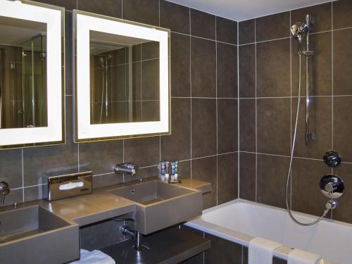 a bathroom with two sinks and a bath tub at Novotel London Brentford in Brentford