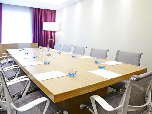a conference room with a large wooden table and chairs at Novotel London Brentford in Brentford