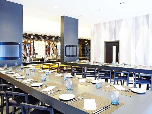 a large dining room with a long table and chairs at Novotel London Brentford in Brentford