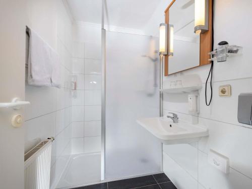 a white bathroom with a sink and a shower at ibis Kassel Melsungen in Melsungen