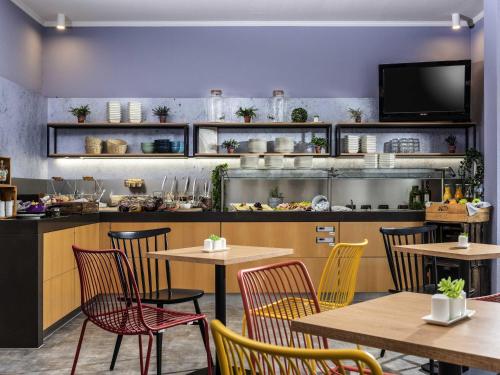 a restaurant with tables and chairs and a counter at ibis Kassel Melsungen in Melsungen