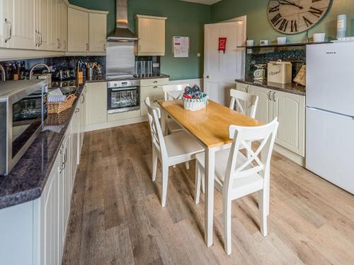 a kitchen with a wooden table and white appliances at Littlebay Apartment in Oban