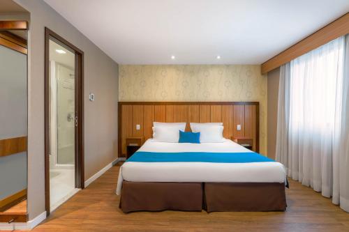 a bedroom with a large bed and a walk in shower at Wyndham Sao Paulo Ibirapuera Convention Plaza in Sao Paulo