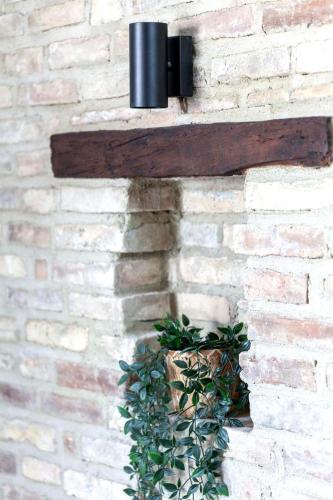 a light on a brick wall with a plant at Charming Boutique B&B Hotel in Villalfonsina