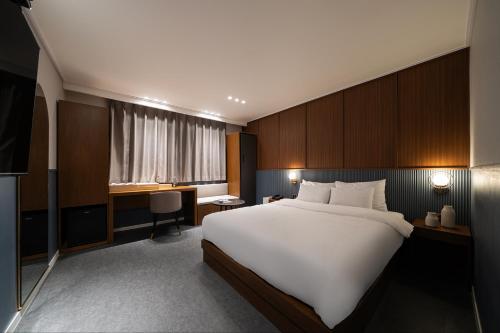 a bedroom with a large white bed and a desk at Browndot Incheon Airport New City in Incheon