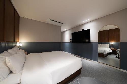 a bedroom with a white bed and a television at Browndot Incheon Airport New City in Incheon