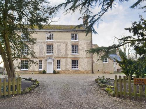 an old stone house with a gate and trees at Hall Farm in Watlington