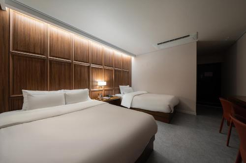 a hotel room with two beds and a desk at Browndot Incheon Airport New City in Incheon