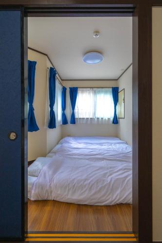 a bedroom with a large bed with blue curtains at Yunosawa HOUSE in Kusatsu