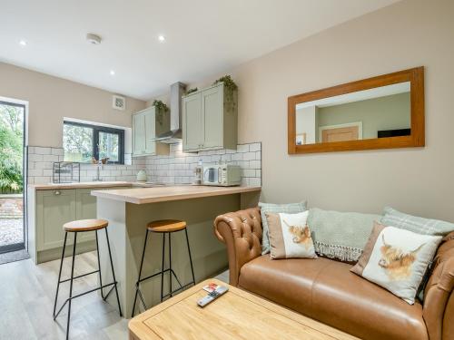 Una sala de estar con un sofá y una cocina. en Wisteria Cottage, en South Cerney