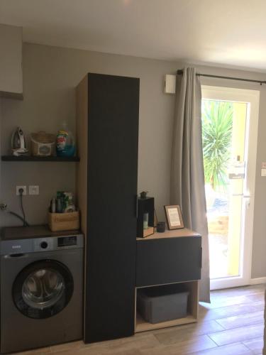a laundry room with a washing machine and a window at Espace Acu-Nature in Saint-Évarzec