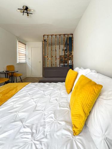 a large white bed with yellow pillows on it at Tottenham City Stays, Opposite Seven Sisters Train Station in London