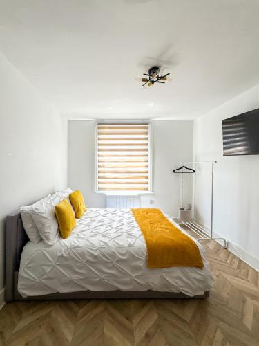 a bedroom with a bed with yellow sheets and a window at Tottenham City Stays, Opposite Seven Sisters Train Station in London