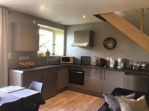 a kitchen with stainless steel appliances and a table with chairs at Espace Acu-Nature in Saint-Évarzec