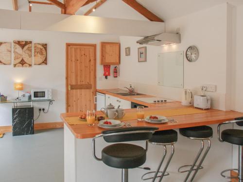 a kitchen with a wooden counter and bar stools at Haycart Barn in Long Stratton