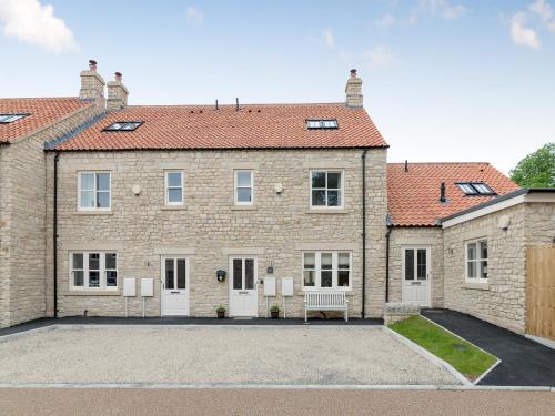 a large brick house with a bench in the driveway at Rye Cottage in Helmsley