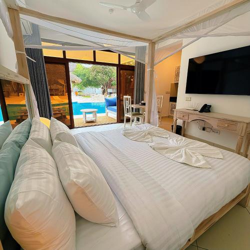 a bedroom with a large bed with a flat screen tv at Jumeirah Malindi Hotel in Malindi