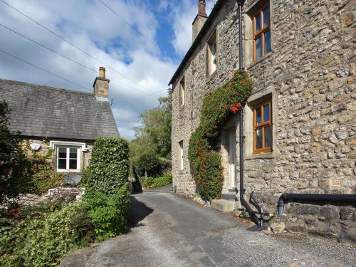 un vecchio edificio in pietra con dei fiori sul lato di Ivy Cottage a Settle