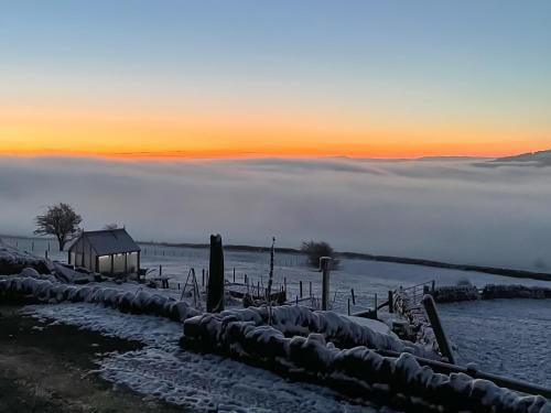 a foggy field with a barn in the foreground with a sunset at Kinder in Mellor