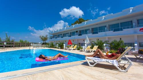 two people laying in chairs in the swimming pool at a hotel at Side Beach Club in Side