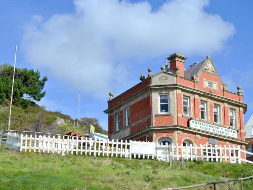 an old brick building on a hill with a white fence at Cliff Railway Apartment in Aberystwyth