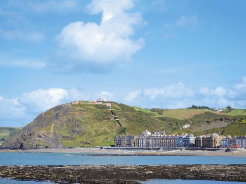 a building on a hill next to the water at Cliff Railway Apartment in Aberystwyth