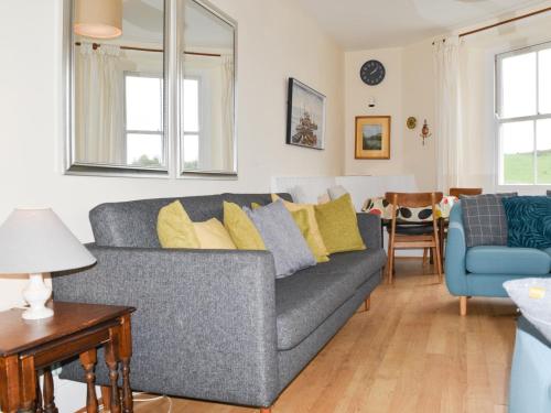 a living room with a gray couch and yellow pillows at Church St 1 Upper Apartment - Cottage in Salcombe