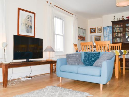 a living room with a blue couch and a tv at Church St 1 Upper Apartment - Cottage in Salcombe