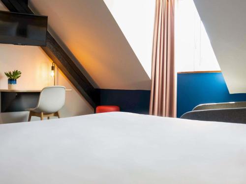 a room with a bed and a table and chairs at Ibis Styles Colmar Centre in Colmar
