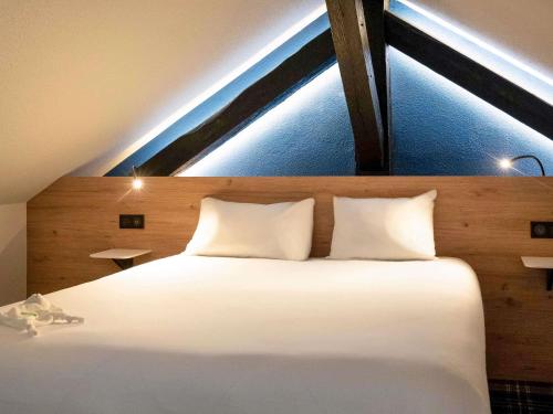 a bedroom with a large white bed with a window at Ibis Styles Colmar Centre in Colmar