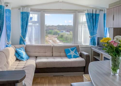 a living room with a couch and a large window at Anchor Park in Happisburgh