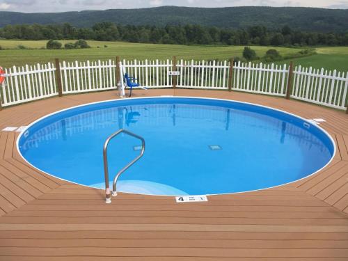 a large swimming pool on a wooden deck with a fence at Apple Inn and Suites Cooperstown Area in Milford