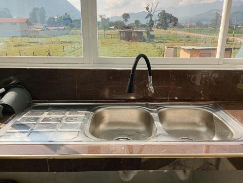 a kitchen sink with a faucet in front of a window at Casa campo in Oxapampa