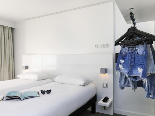 a bedroom with a bed with a book and glasses on it at Ibis Styles Menton Centre in Menton